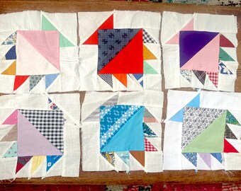 Può includere: Nove quadrati di tessuto, ognuno con un diverso design a patchwork, con una varietà di colori e motivi, tra cui rosso, blu, verde, viola, rosa e bianco.
