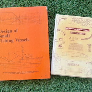 Könnte beinhalten: Zwei Vintage-Bücher auf einer grünen Oberfläche. Das orangefarbene Buch trägt den Titel "Design of Small Fishing Vessels" mit einer Bootsillustration. Das andere Buch trägt den Titel "Boatbuilding Manual" mit Diagrammen. Beide Bücher beziehen sich auf nautisches Design.