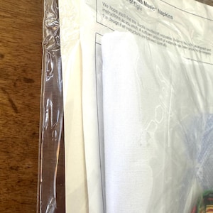 Może przedstawiać: Białe opakowanie z białą serwetką w środku. Na opakowaniu widnieje napis "82990 "Christmas Music" Napkins Set of Eight".
