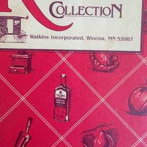 May include: A red and cream-colored recipe collection cover with the words "Recipe Collection" in large red letters. The cover features illustrations of kitchen items and a bottle of vanilla extract. The text "Watkins Incorporated, Winona, MN 55987" is also visible.