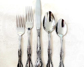 May include: A set of five silver-plated flatware pieces, including a knife, two forks, and two spoons. The handles are ornate and feature a floral design.
