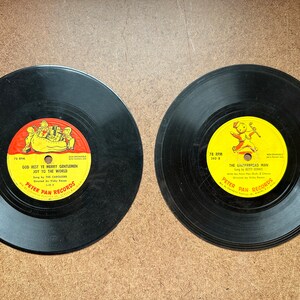 May include: Two black vinyl records with yellow and red labels. The first record has the text "God Rest Ye Merry Gentlemen Joy To The World" and the second record has the text "The Gingerbread Man". Both records are from Peter Pan Records.