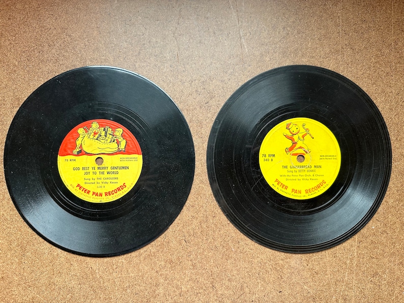 May include: Two black vinyl records with yellow and red labels. The first record has the text "God Rest Ye Merry Gentlemen Joy To The World" and the second record has the text "The Gingerbread Man". Both records are from Peter Pan Records.