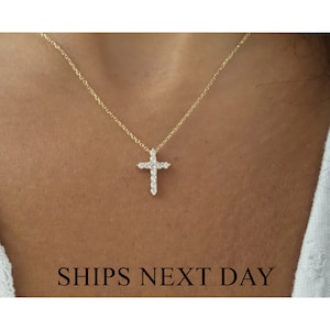 May include: A gold chain necklace with a small, diamond-encrusted cross pendant.