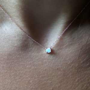Puede incluir: Un delicado collar de cadena de plata con un peque&ntilde;o colgante redondo de &oacute;palo blanco.