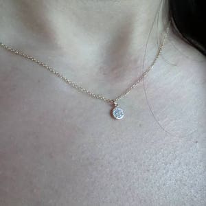Op de afbeelding: Een delicate gouden ketting met een klein, rond hangertje bezet met kleine diamanten.