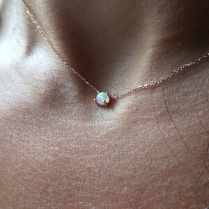 Puede incluir: Un delicado collar de oro rosa con un peque&ntilde;o colgante de &oacute;palo blanco.