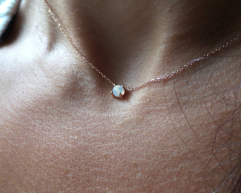 Puede incluir: Un delicado collar de oro rosa con un peque&ntilde;o colgante de &oacute;palo blanco.