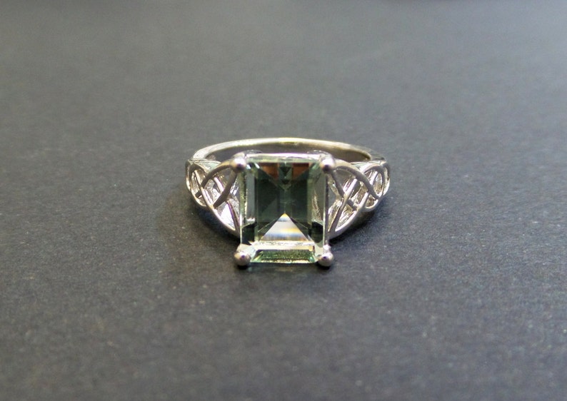 May include: A silver ring with a Celtic knot design and a green gemstone in the center.