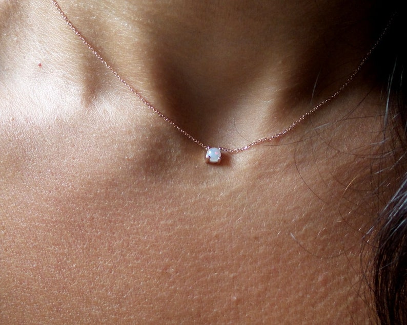 Puede incluir: Un delicado collar de cadena de oro con un peque&ntilde;o colgante de &oacute;palo blanco.
