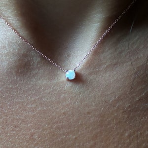 Puede incluir: Un delicado collar de cadena de oro rosa con un peque&ntilde;o colgante redondo de &oacute;palo blanco.