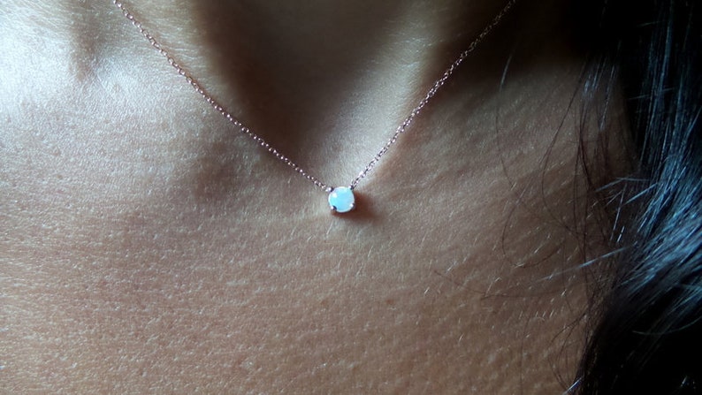 Puede incluir: Un delicado collar de cadena de oro rosa con un peque&ntilde;o colgante redondo de &oacute;palo blanco.