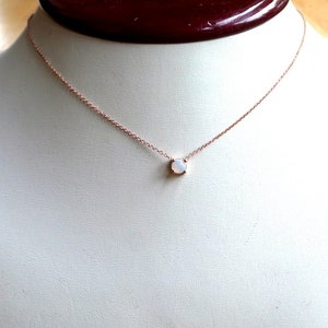 Puede incluir: Un delicado collar de oro rosa con un peque&ntilde;o colgante de &oacute;palo blanco.