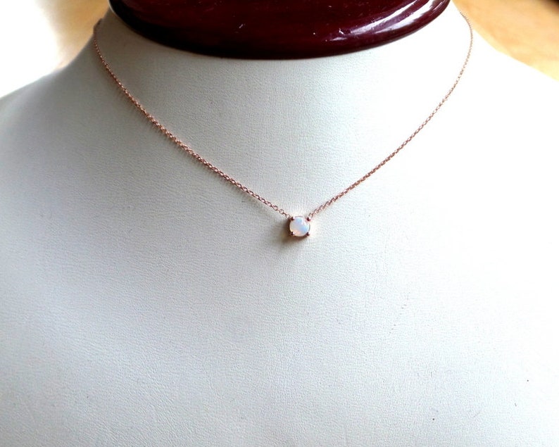 Puede incluir: Un delicado collar de oro rosa con un peque&ntilde;o colgante de &oacute;palo blanco.