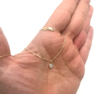 Puede incluir: Un delicado collar de cadena de oro con un pequeño colgante redondo engastado con pequeños diamantes.
