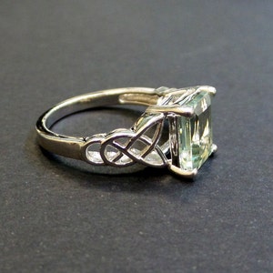 May include: A silver ring with a green gemstone set in a Celtic knot design.