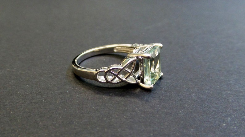 May include: A silver ring with a green gemstone set in a Celtic knot design.