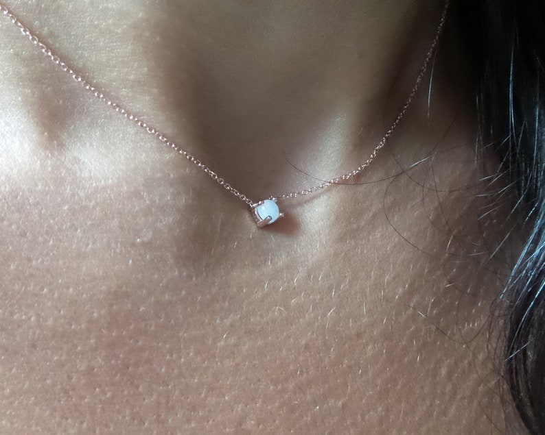 Puede incluir: Un delicado collar de cadena de oro rosa con un peque&ntilde;o colgante de &oacute;palo blanco.