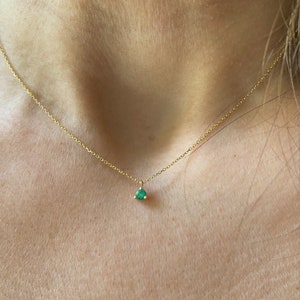 May include: A delicate gold chain necklace with a small, round, green gemstone pendant.
