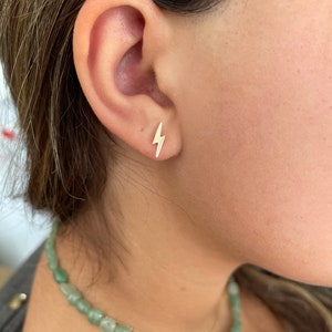 May include: Gold lightning bolt stud earrings. The earrings are small and delicate, and they are perfect for adding a touch of edgy style to any outfit.