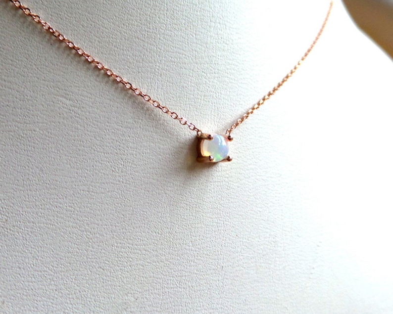 Puede incluir: Un delicado collar de cadena de oro rosa con un peque&ntilde;o colgante de &oacute;palo de forma ovalada.