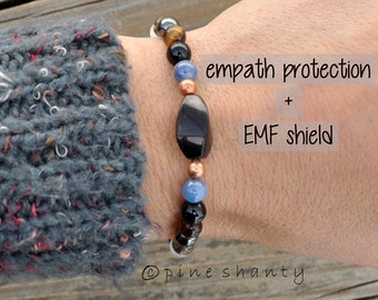 May include: A beaded bracelet with black onyx, tiger's eye, hematite, copper, and blue stones. The bracelet is labeled "empath protection + EMF shield".