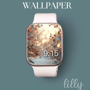 Puede incluir: Un Apple Watch blanco con una banda dorada que muestra una escena invernal con bayas rojas y un fondo borroso. La hora es 9:15 y la fecha es 16 de diciembre. El texto "lilly ASHLEY" está debajo del reloj.