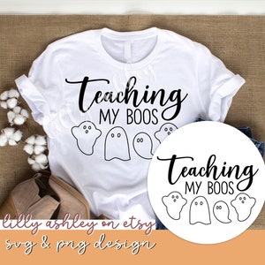 May include: White t-shirt with black text that reads "Teaching My Boo's" with three ghost illustrations. A separate white circle with the same text and ghost illustrations.
