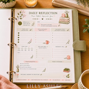 May include: A daily reflection planner page in a sage green binder featuring sections for gratitude, wins, challenges, self-care, and daily thoughts. The page includes floral illustrations, candles, and books with text reading Daily Reflection.