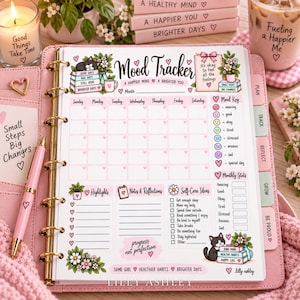 May include: A pink ring-bound planner featuring a Mood Tracker page with illustrations of cats, flowers, and hearts. The page includes sections for a monthly calendar, mood key, highlights, notes, self-care ideas, and monthly stats with text.