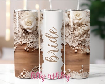 May include: White tumbler with a woodgrain background, white lace, and a white rose. The word "bride" is written in brown script on the tumbler.