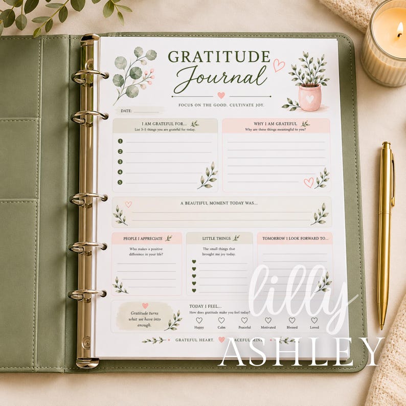 Op de afbeelding: Een dankbaarheidsdagboekpagina in een saliegroene map met een gouden ringmechanisme. De pagina bevat de tekst Gratitude Journal, secties voor dagelijkse reflecties, lijsten voor dankbaarheid en kleine illustraties van planten.
