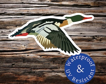 Puede incluir: Una pegatina de un pato merganser de cabeza verde en vuelo con un contorno blanco. La pegatina tiene un círculo azul con el texto "Waterproof & UV Resistant" en blanco.