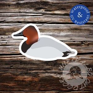 May include: A sticker featuring a stylized illustration of a Canvasback duck. The duck has a red head, black beak, and gray body. The sticker is labeled "Waterproof & UV Resistant" in a blue circle. The background is a weathered wood texture.