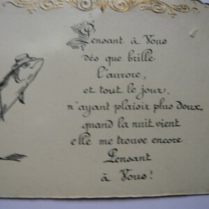 K&ouml;nnte beinhalten: Eine Vintage-Karte mit einer Schwarzwei&szlig;illustration eines Fisches, der einen Hut tr&auml;gt und einen Stock h&auml;lt. Die Karte hat einen goldenen Rand und enth&auml;lt ein handgeschriebenes Gedicht auf Franz&ouml;sisch, das lautet: "Pensant &agrave; Vous d&egrave;s que brille l'aurore, et tout le jour. n'ayant plaisir plus doux, quand la nuit vient elle me trouve encore Pensant &agrave; Vous!"