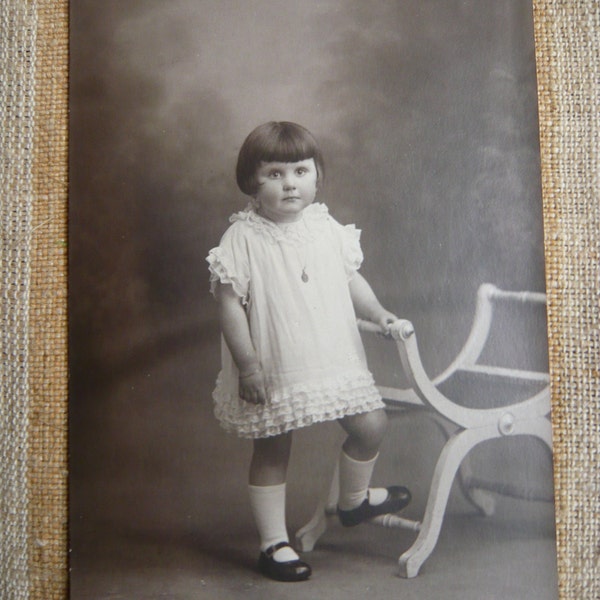 Photo d'une petite fille vêtue de blanc années aux chaussures vernies noires coupe de cheveux Années folles 1920 collection photos rétro