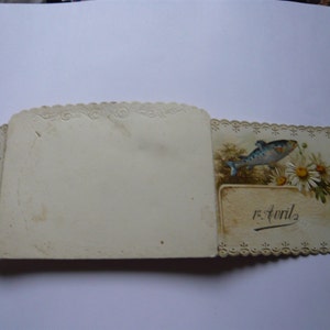 K&ouml;nnte beinhalten: Eine vintage, wei&szlig;e Karte mit Spitzenrand, einer Illustration eines blauen und wei&szlig;en Fisches und dem Text "5 Avril" auf der rechten Seite.