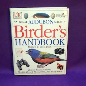 May include: A hardcover book titled "Birder's Handbook" by the National Audubon Society. The cover features a colorful bird illustration, binoculars, and a camera. The book's subtitle is "How to Locate, Observe, Identify, Record, Photograph, and Study Birds."