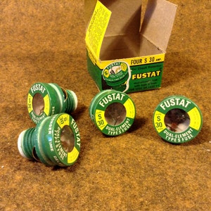 May include: Four green and yellow FUSTAT dual-element type S fuses, each rated for 30 amps. The fuses are on a brown surface. The box reads "FOUR S 30 AMP. For Circuit Protection FUSTAT Dual-element type S fuse with type A holder FOR 125V OR LESS."