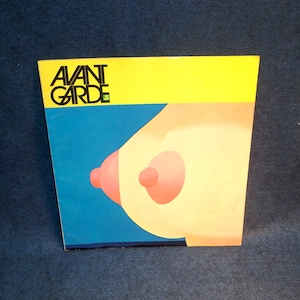 May include: A vintage album cover with the word "AVANT GARDE" in black letters on a yellow and blue background. The cover features a stylized illustration of a breast in shades of peach and pink.