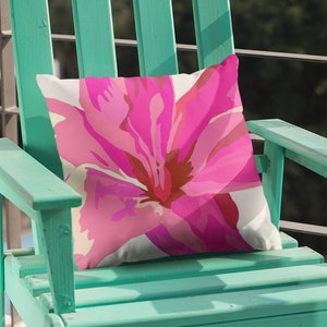 May include: A teal green wooden adirondack chair with a pink floral pillow. The chair is on a black and white tiled patio.