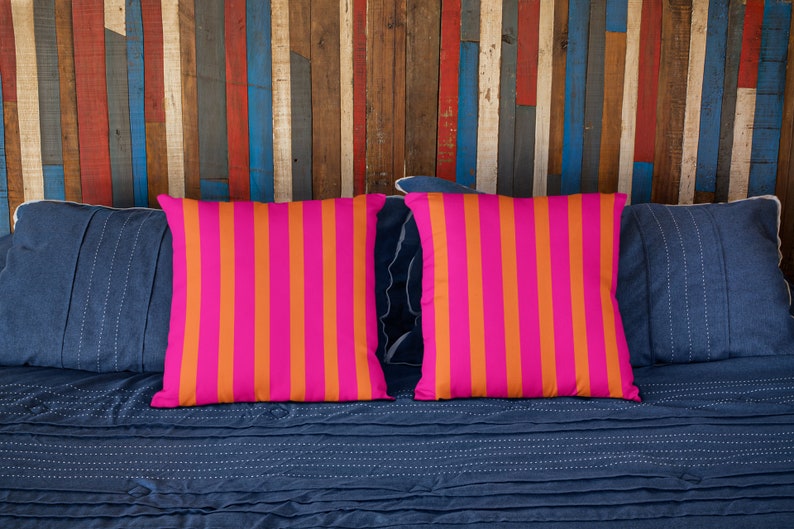 May include: Two pink and orange striped throw pillows on a blue bed with a wooden headboard.