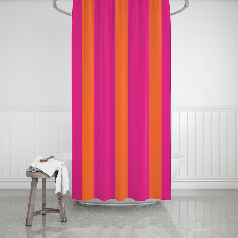 May include: A pink and orange striped shower curtain hangs in a bathroom. The curtain is made of a soft, fabric material.