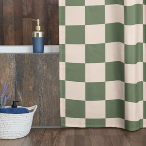 May include: A green and white checkered shower curtain hangs in a bathroom with a wooden wall and a white bathtub. A basket with lavender and a blue towel sits on the floor.