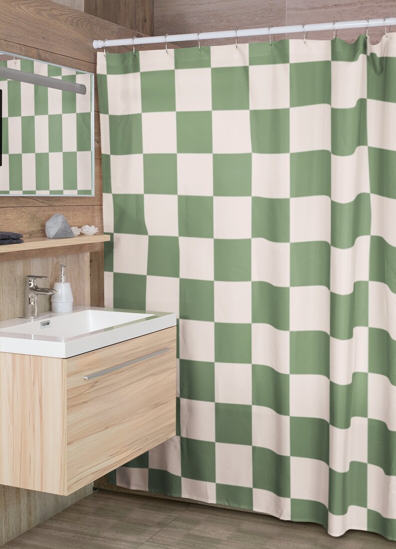 May include: A green and white checkered shower curtain hangs in a bathroom. The curtain is made of a soft, fabric material. The shower curtain is hung on a white shower rod.