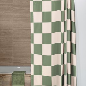 May include: A green and white checkered shower curtain with a simple design. The curtain is hung on a silver shower rod.