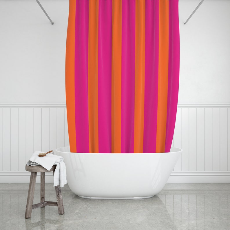 May include: A white bathtub with a pink and orange striped shower curtain in a white bathroom.