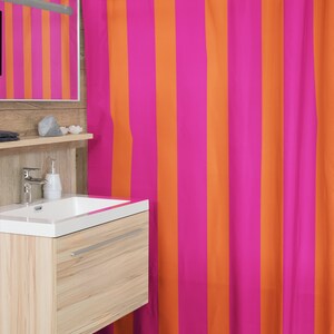 May include: A pink and orange striped shower curtain. The curtain is made of a soft, water-resistant fabric and is perfect for adding a pop of colour to any bathroom.