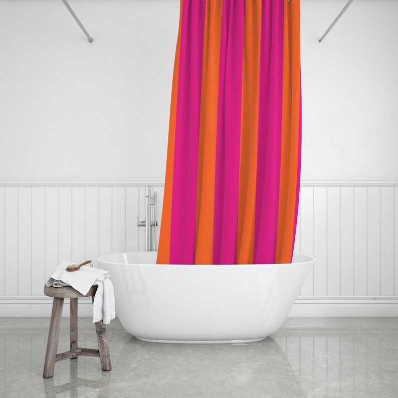 May include: A white bathtub with a pink and orange striped shower curtain hanging over the side. The bathtub is in a white bathroom with white tiled walls.
