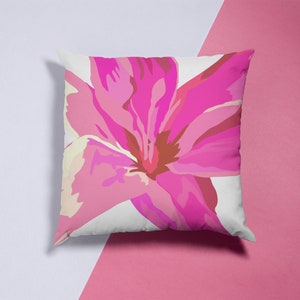 May include: A white pillow with a pink flower design. The flower has a pink and white center and petals.